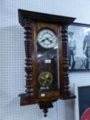 A WALNUT CASED VIENNA WALL CLOCK, HAVING WHITE ROMAN NUMERAL FACE AND BRASS PENDULUM, WITH KEY