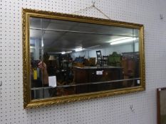 A GILT FRAMED OBLONG WALL MIRROR WITH CUT LINE BORDERS