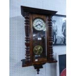 A WALNUT CASED VIENNA WALL CLOCK, HAVING WHITE ROMAN NUMERAL FACE AND BRASS PENDULUM, WITH KEY