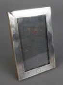 GEORGE V SILVER EASEL PHOTOGRAPH FRAME, oblong with engine turned decoration, small plain circular