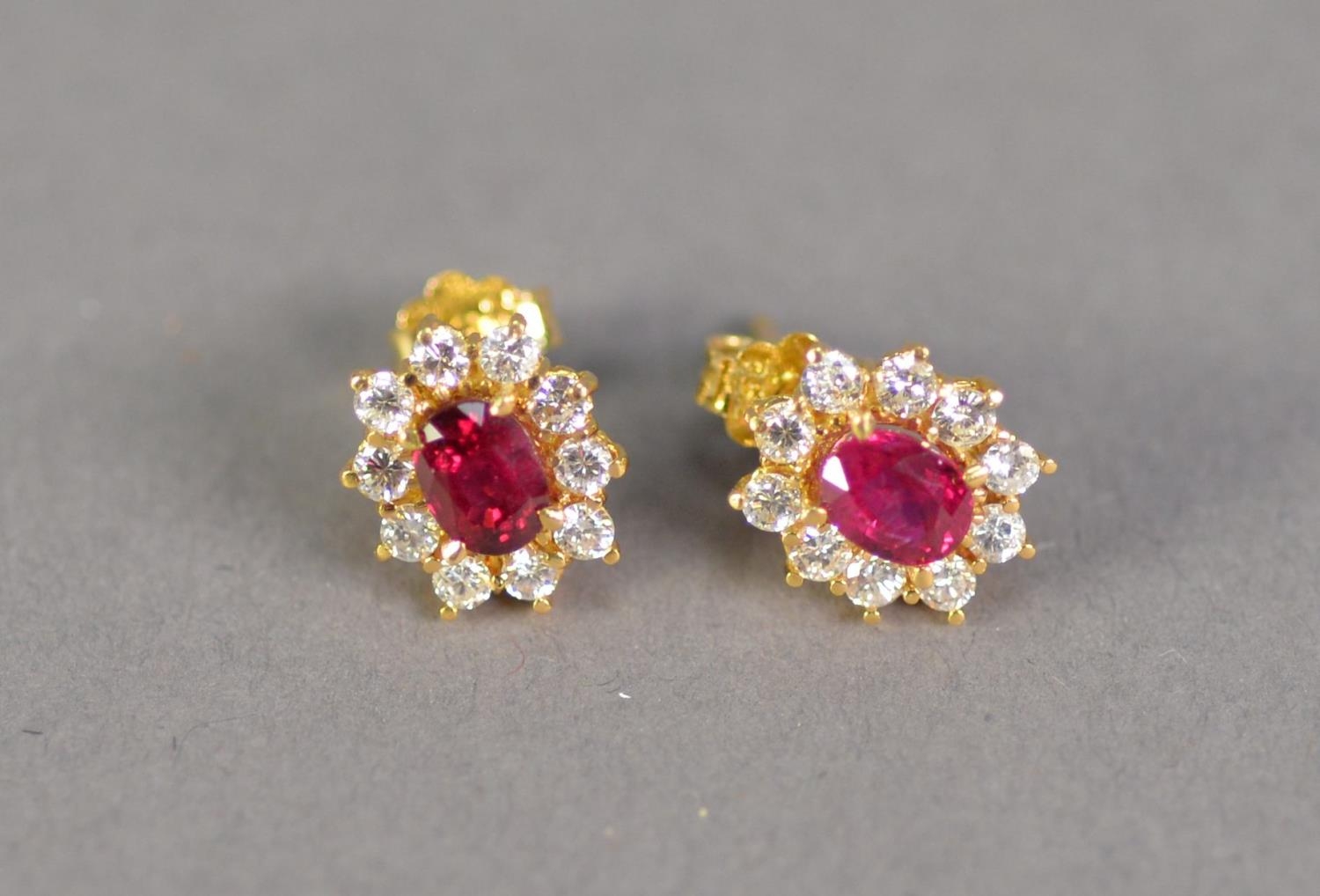 PAIR OF .750 STAMPED GOLD EARRINGS each set with a small ruby within a surround of ten tiny