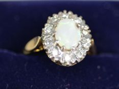 18CT GOLD RING WITH A CENTRAL CLAW -SET OPAL within a surround of ten small diamonds, 6.0gms gross