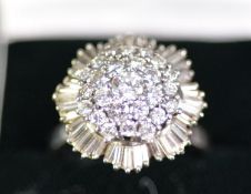 WHITE GOLD COLOURED METAL (unmarked) AND DIAMOND CLUSTER RING with domed three tier centre, the