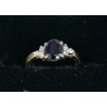 18ct WHITE GOLD RING, set with an oval dark blue sapphire and a trio of small diamonds to each