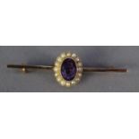 A GOLD COLOURED METAL BAR BROOCH, set with centre oval cluster with oval amethysts and surround of