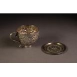 UNMARKED INDIAN EMBOSSED SILVER COLOURED METAL TEACUP, of typical form, profusely decorated with