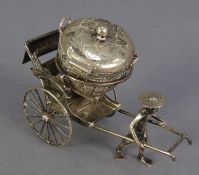 CHINESE SILVER COLOURED METAL NOVELTY CONDIMENT RECEIVER, modelled as a man pulling a large, lidded,