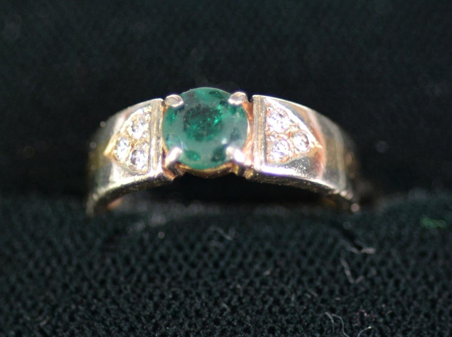 14ct GOLD RING with centre round dark green emerald, the shoulder each with a triangular setting