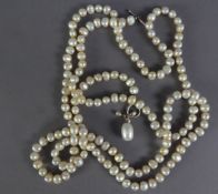 LONG, SINGLE STRAND NECKLACE OF CULTURED BAROQUE PEARLS of roughly uniform size, with metal ring and