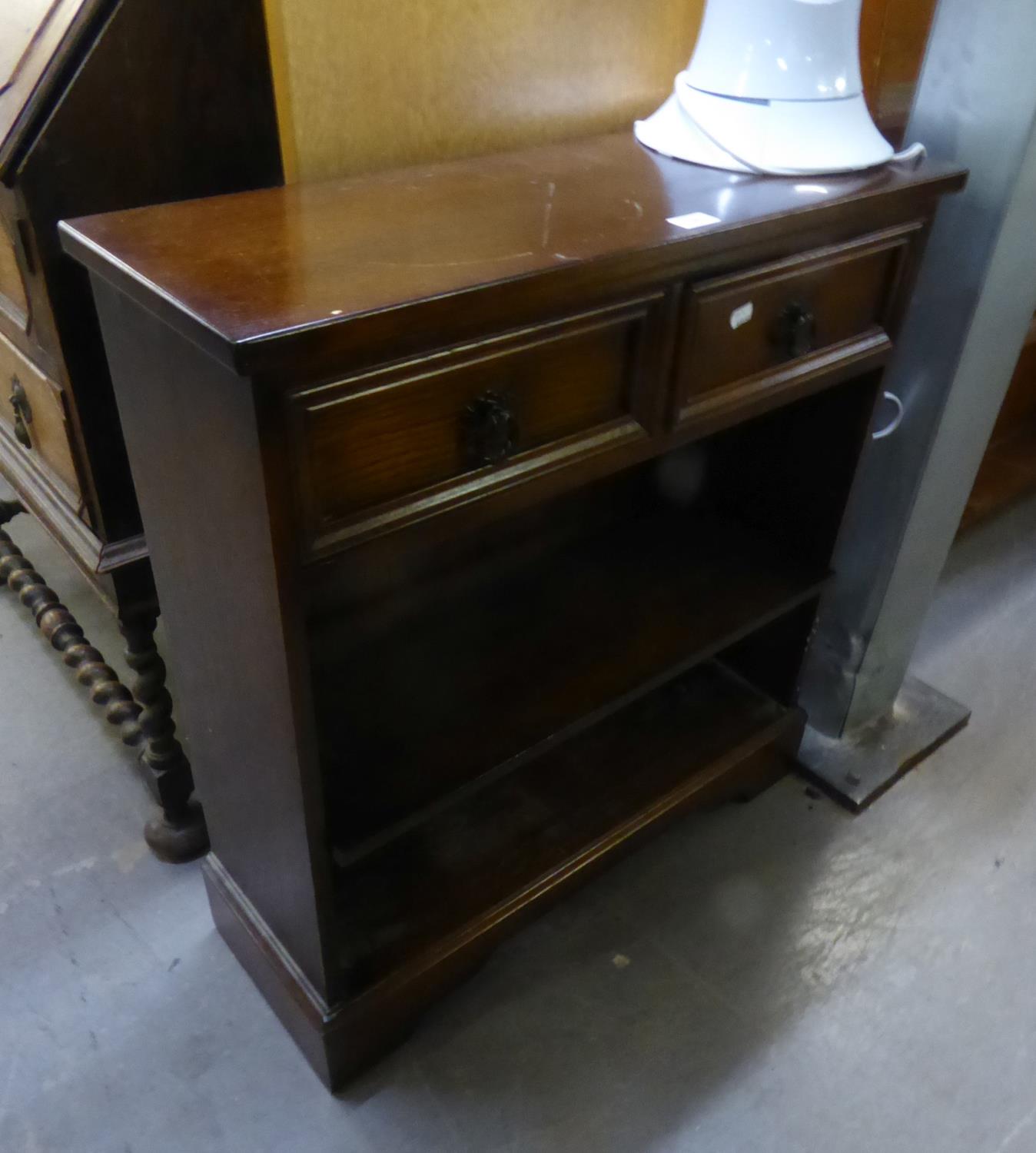 AN OAK CARVED SMALL OPEN BOOKCASE, having two drawers, shelving on bracket feet