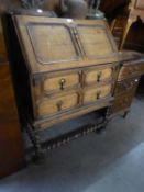 AN OAK BUREAU OF JACOBEAN STYLE WITH SPIRAL LEGS AND STRETCHERS