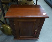 A SMALL DARK STAINED CUPBOARD WITH SINGLE PANEL DOOR