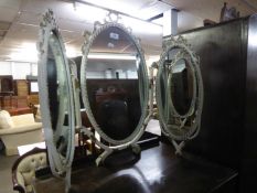 A TRIPLE OVAL TOILET MIRROR, IN WHITE AND GILT FRAMES, WITH RIBBON BOW PEDIMENTS