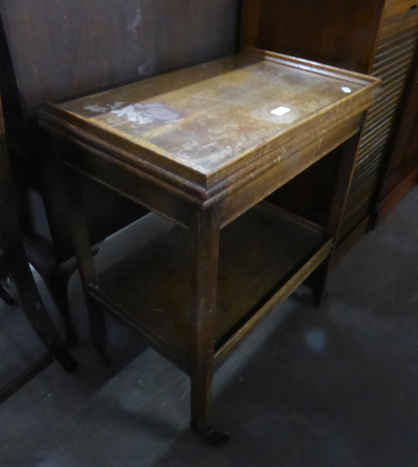 AN OAK TWO TIER TEA TROLLEY WITH SWIVEL AND FLAP-TOP TO FORM A CARD TABLE