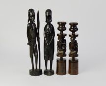 PAIR OF TANZANIAN CARVED HARDWOOD FIGURAL CANDLESTICKS, each of cylindrical form, carved with a pair
