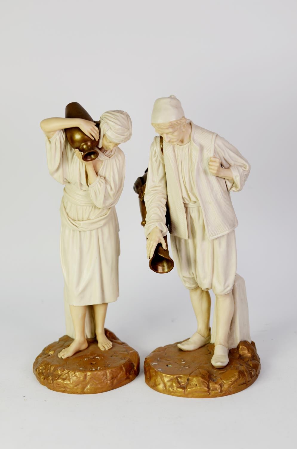 PAIR OF EARLY 20th CENTURY ROYAL WORCESTER CHINA FIGURES of male and female water carriers, cream