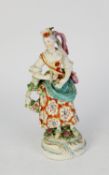 18th CENTURY DERBY CHINA FEMALE FIGURE, holding a triangle and wearing a shoulder bag, floral