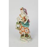 18th CENTURY DERBY CHINA FEMALE FIGURE, holding a triangle and wearing a shoulder bag, floral