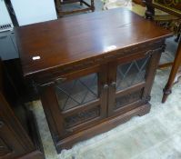 A CARVED MAHOGANY SMALL CUPBOARD ENCLOSED BY TWO LEAD LIGHT GLAZED DOORS WITH CARVED LOWER PANELS (