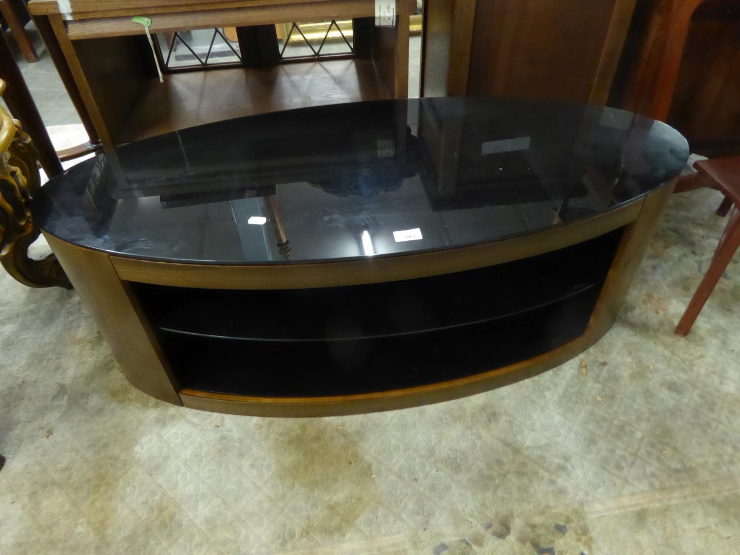 AN OVAL TV STAND WITH BLACK GLASS TOP AND SHELVES