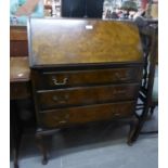 A FIGURED WALNUT BUREAU WITH THREE LONG DRAWERS, ON CABRIOLE SUPPORTS