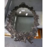 AN OVAL WALL MIRROR, IN CAST LEAD FRUITING VINE PATTERN FRAME WITH RING HANGER AND MATCHING WALL
