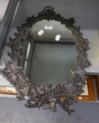 AN OVAL WALL MIRROR, IN CAST LEAD FRUITING VINE PATTERN FRAME WITH RING HANGER AND MATCHING WALL