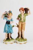 PAIR OF MODERN CAPODIMONTE PAINTED BISQUE PORCELAIN FIGURES, he modelled carrying a basket of grapes