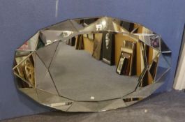 AN OVAL BEVELLED EDGE LARGE WALL MIRROR, WITH BROAD FACETED MIRROR GLASS BORDER