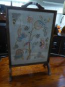 AN OAK FRAMED EMBROIDERED FIRE-SCREEN