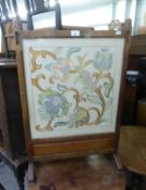 AN OAK CHEVAL GRATE SCREEN WITH GLAZED AND NEEDLEWORK PANEL
