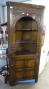 A CARVED OAK DOUBLE CORNER CUPBOARD WITH OPEN SHELVES OVER A CUPBOARD