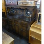 AN OAK COURT CUPBOARD, THE CANOPY TOP HAVING TWO LEAD LIGHT DOORS AND A CENTRE PANEL DOOR, THE