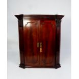 GEORGE III FIGURED AND CARVED MAHOGANY CORNER CUPBOARD, the moulded cornice above a pair of flame