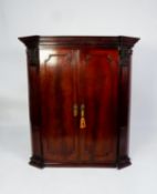 GEORGE III FIGURED AND CARVED MAHOGANY CORNER CUPBOARD, the moulded cornice above a pair of flame