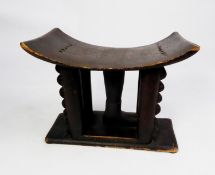 TWENTIETH CENTURY AFRICAN DARK STAINED AND CARVED SOFTWOOD STOOL, the shaped seat raised on four