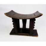 TWENTIETH CENTURY AFRICAN DARK STAINED AND CARVED SOFTWOOD STOOL, the shaped seat raised on four