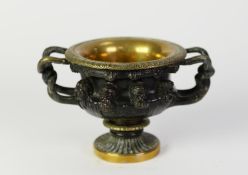 PATINATED AND GILT BRONZE MODEL OF AN ORNATE TWO HANDLED PEDESTAL VASE, SIMILAR TO THE WARWICK VASE,