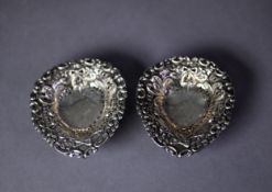 PAIR OF SILVER COLOURED METAL PIERCED AND REPOUSSÉ HEART SHAPED SWEET MEAT DISHES, each on three