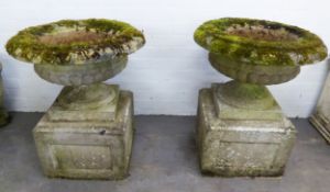 PAIR OF RECONSTITUTED STONE GARDEN URNS of shallow circular form, with moulded turned-over borders