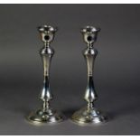 PAIR OF SILVER TABLE CANDLESTICKS each with urn shaped sconces, stepped shoulder, waisted column