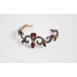 STERLING SILVER BOLD SCROLL PATTERN TORQUE BANGLE, collet set with six variously shaped garnets