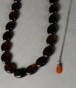 NECKLACE OF DARK BROWN AMBER DISC SHAPED OVAL BEADS, 22? (55.8cm) long (clasp faulty) and a silver