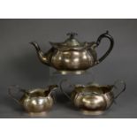 GEORGE V SILVER THREE PIECE TEA SET, oval and embossed with everted wavy edge, the teapot with