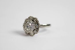 WHITE GOLD COLOURED METAL (unmarked) AND DIAMOND CLUSTER RING with domed three tier centre, the