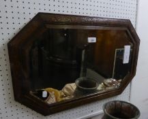 A WALL MIRROR WITH BEVELLED EDGES, CANTED CORNERS IN CARVED OAK FRAME