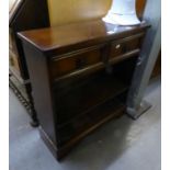 AN OAK CARVED SMALL OPEN BOOKCASE, having two drawers, shelving on bracket feet