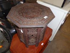 A MIDDLE EASTERN CARVED TEAKWOOD OCTAGONAL COFFEE TABLE, WITH LIFT-OFF TOP, ON FOLDING CARVED AND