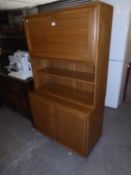 AN ERCOL COCKTAIL CABINET, THE UPPER PORTION HAVING UPRIGHT FALL FRONT OVER TWO OPEN SHELVES, ON