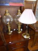 A PAIR OF BRONZE EFFECT LAMPS WITH GLASS BULBOUS SHADES AND A BRASS READING LAMP WITH SWING ARM